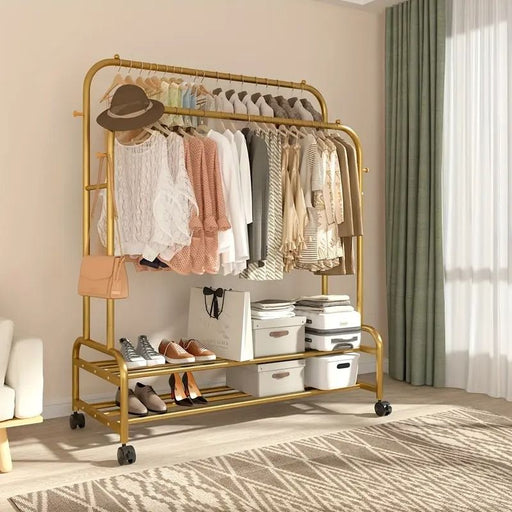 Gold clothing rack with clothes, shoes, and bags in a room with a window and curtain.