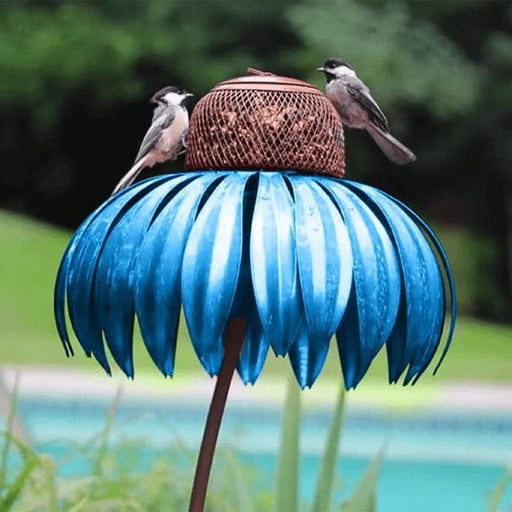 Two birds perched on a decorative blue flower with a blurred natural background